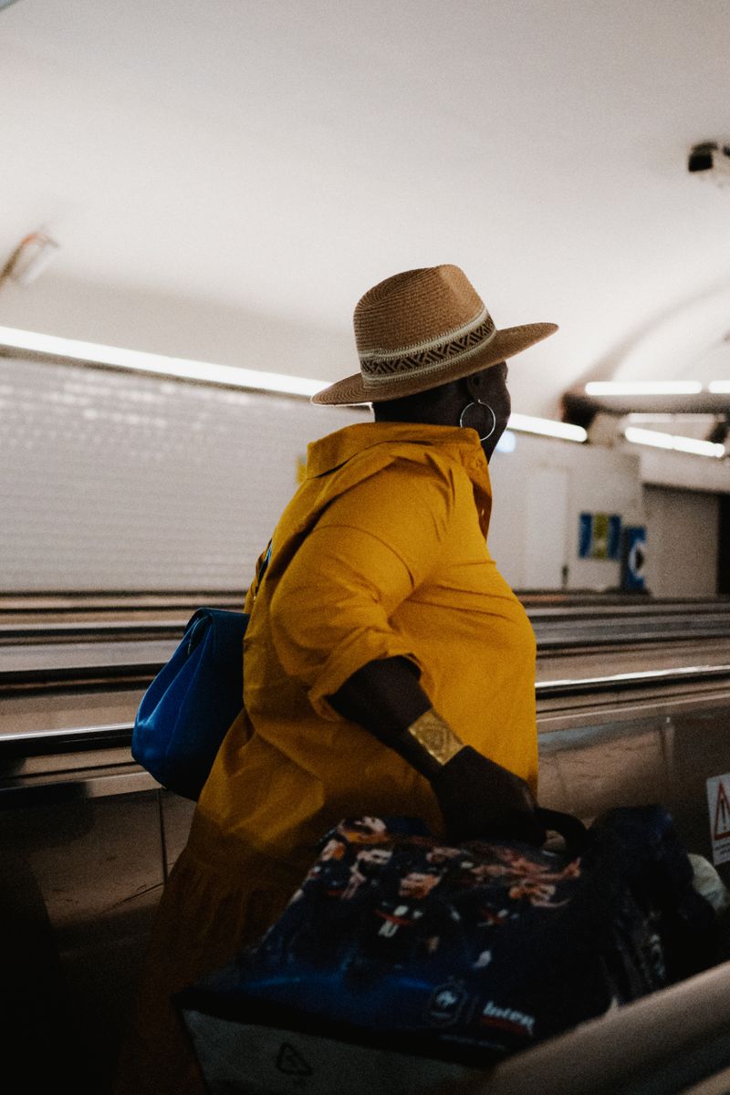 Black woman in yellow coat traveling through airport