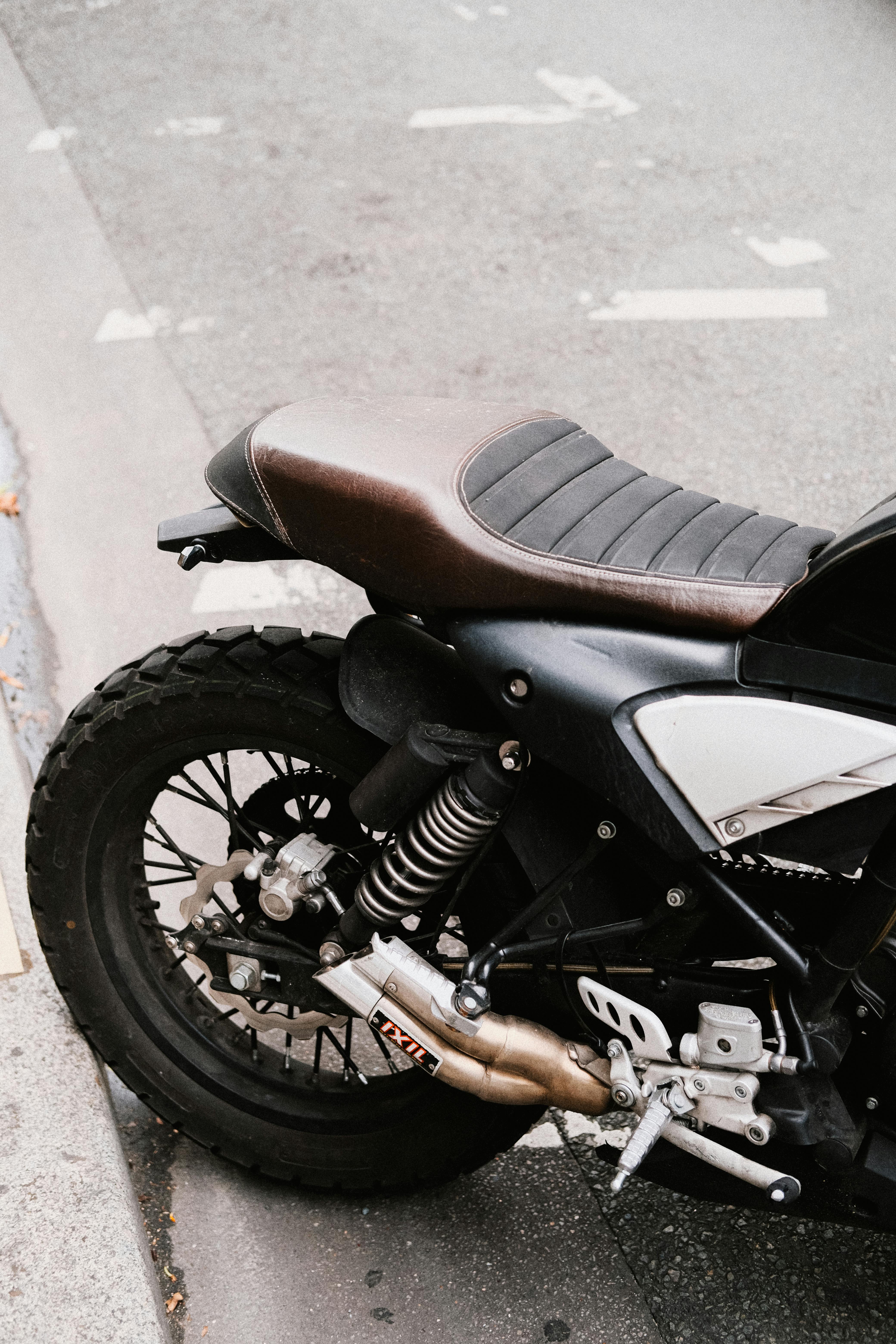 Detailed view of a scrambler motorcycle rear on an urban street corner.