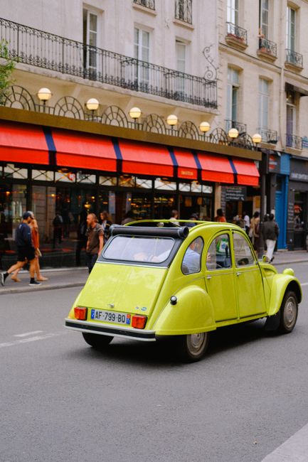 Classic Citroen 2CV cruising urban Paris street, vibrant and timeless.