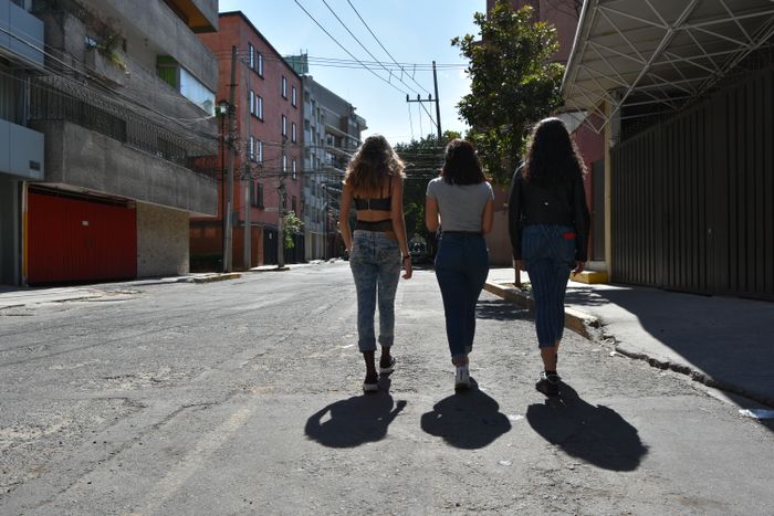 Three people walking down a sunlit street, photo by Israel Torres on Pexels