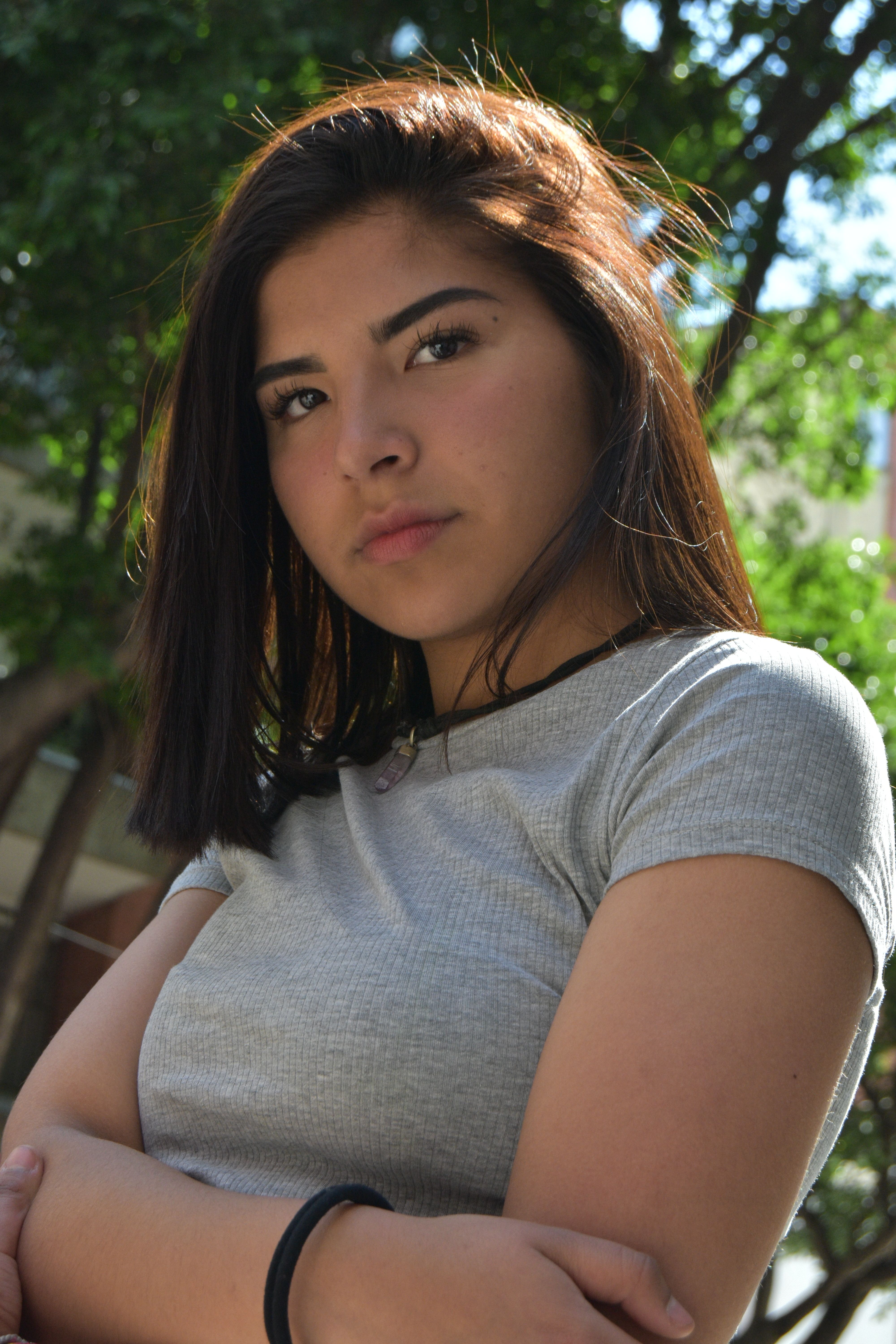 Portrait of a young woman with brown hair and a gray t-shirt, looking confident.