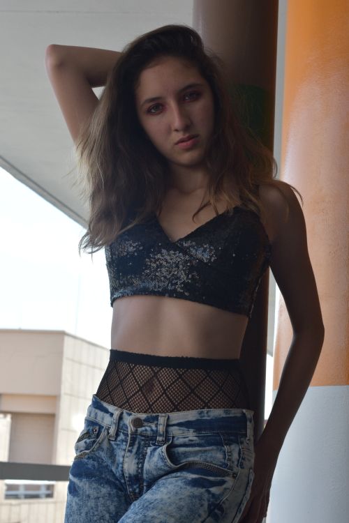 Free Young woman posing in trendy denim and crop top fashion against an urban backdrop. Stock Photo