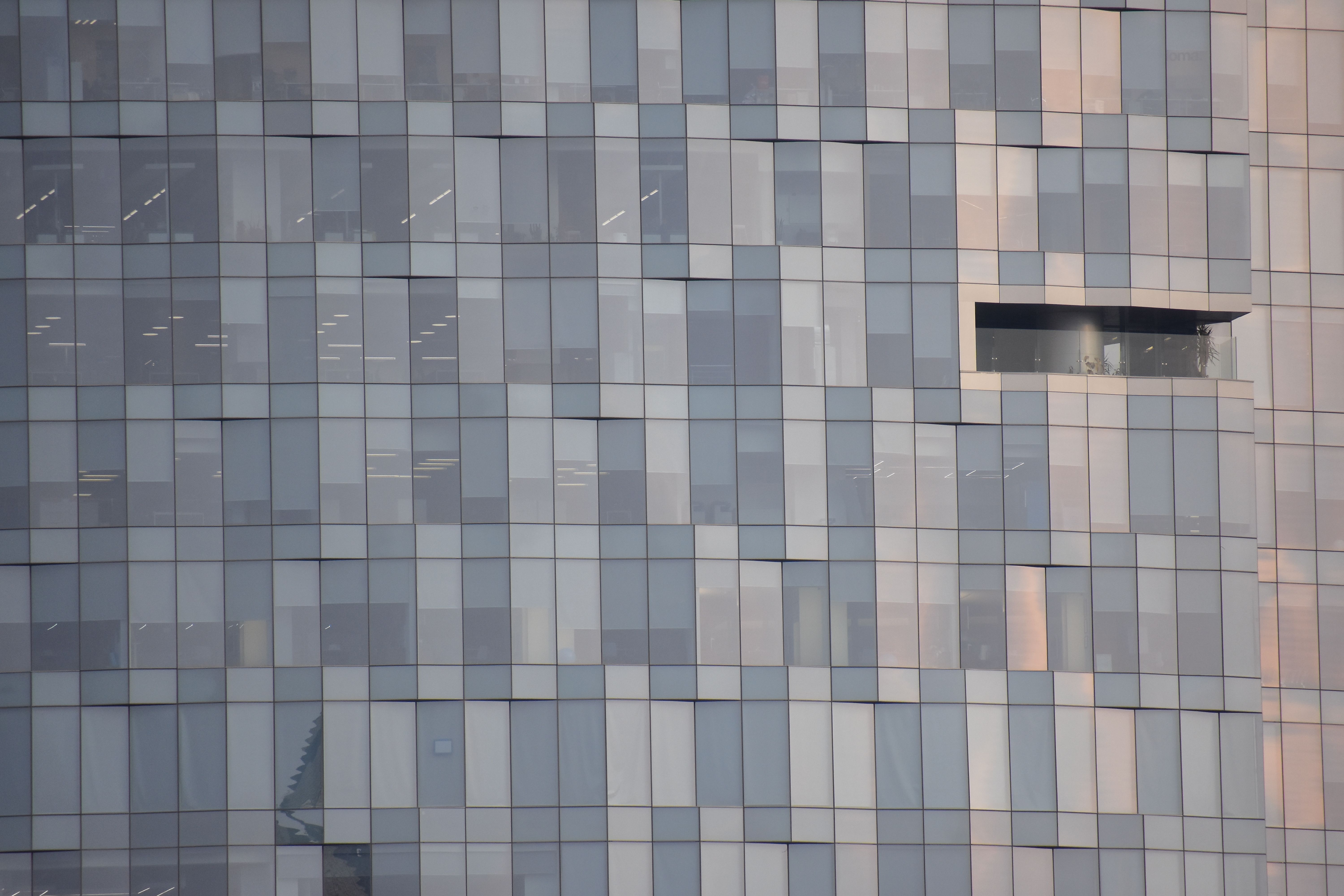 Close-up of a modern glass facade with reflections in an urban setting, showcasing architectural design.