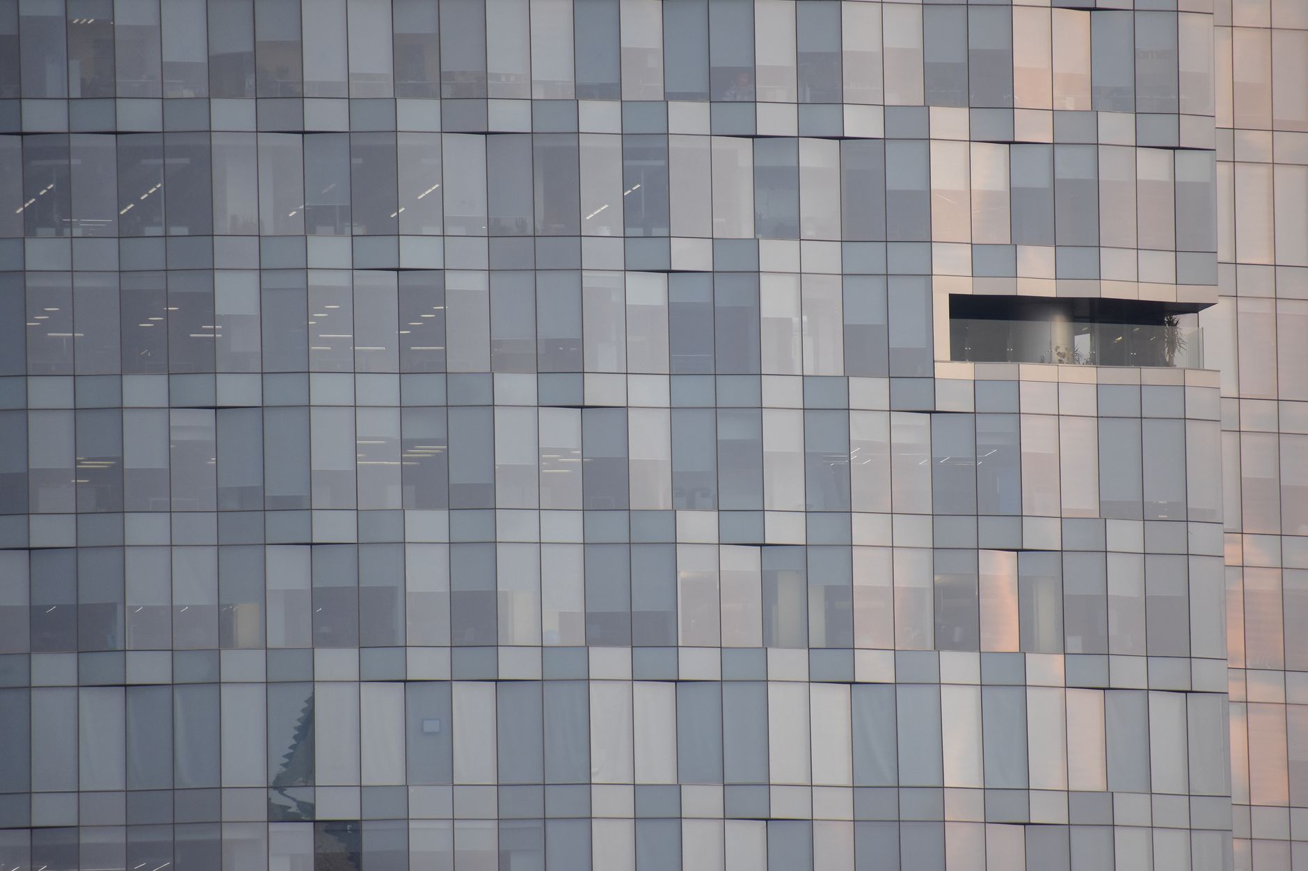 Close-up of a modern glass facade with reflections in an urban setting, showcasing architectural design.