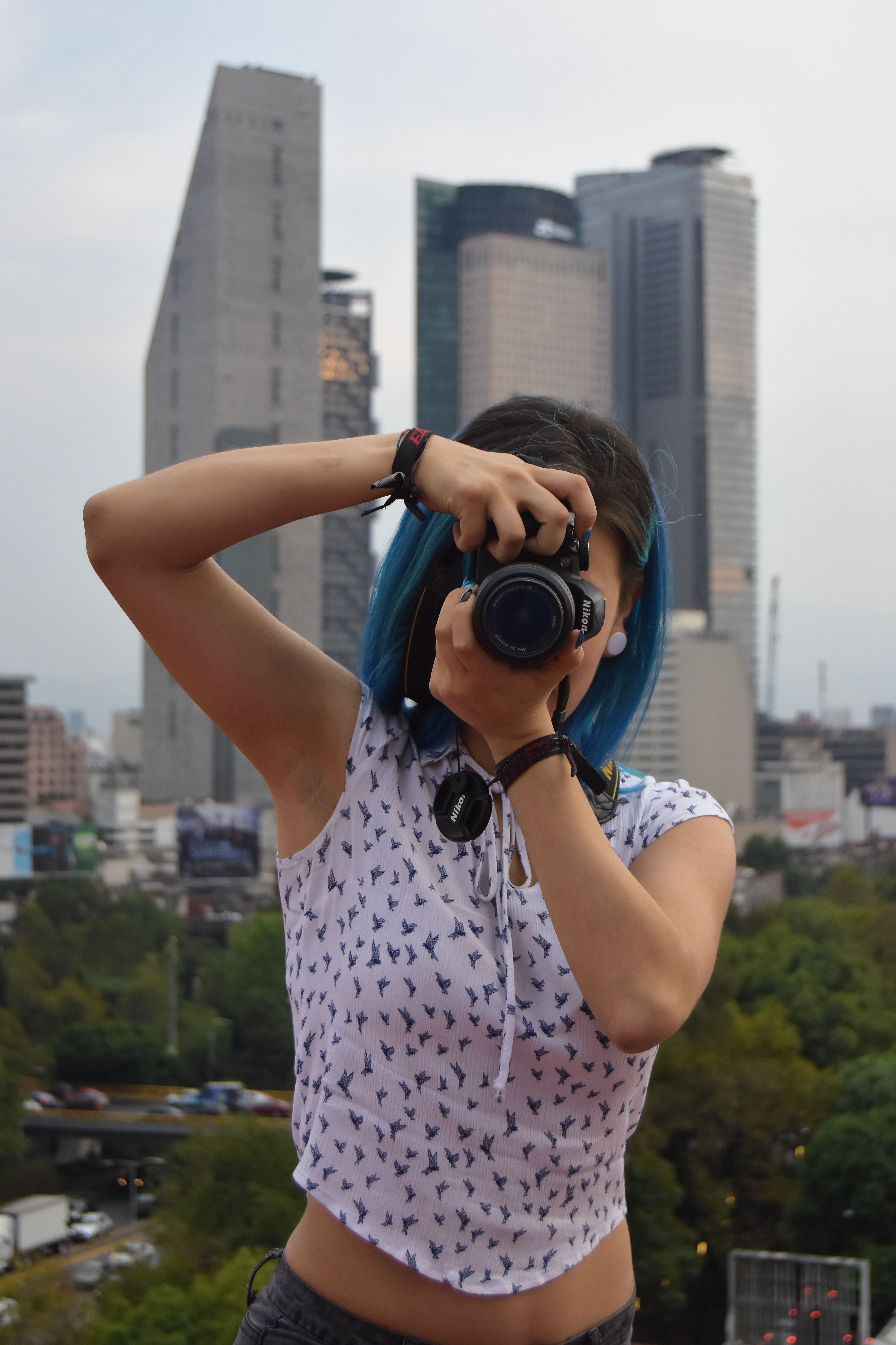 Woman capturing city skyline with camera in vibrant urban setting.
