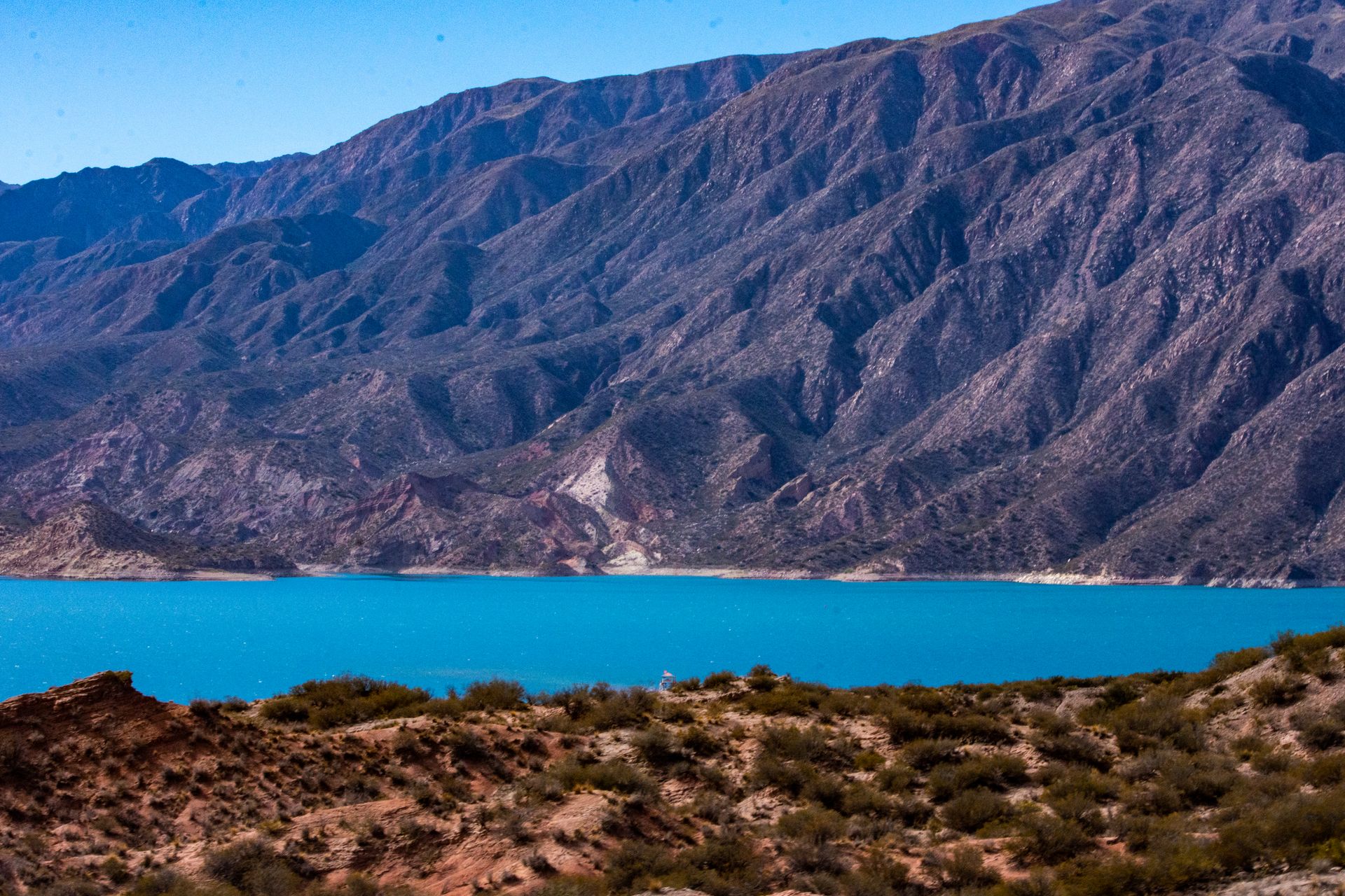 Breathtaking view of towering mountains and vibrant turquoise lake under a clear blue sky.