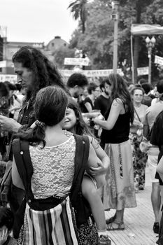 A lively street scene captured in black and white, featuring a diverse crowd in an urban setting.