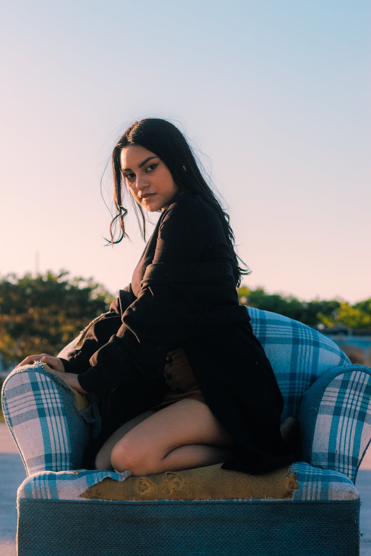 Young Woman Sitting On An Old Broken Armchair Outside 