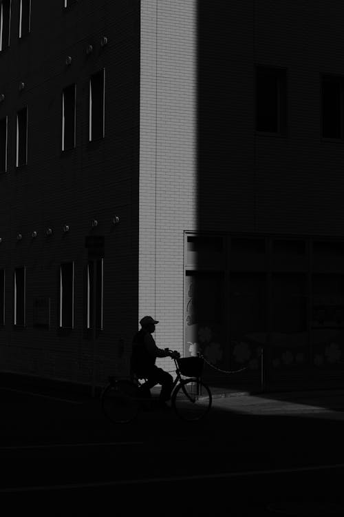 Silhouette of a Man Riding a Bicycle in a City 