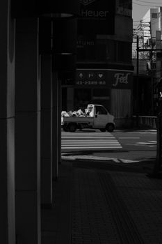 Captivating black and white street view featuring a lone truck on a city street corner, casting shadows.