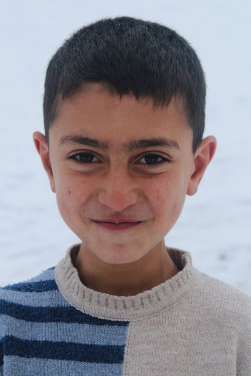 Free Close-up portrait of a smiling boy wearing a striped sweater in a wintry setting. Stock Photo