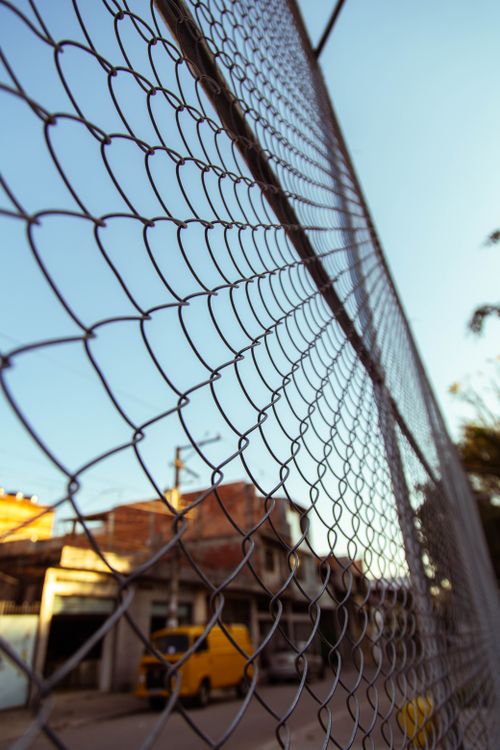Free Chain link fence in an urban setting with blue sky, highlighting city life and boundaries. Stock Photo