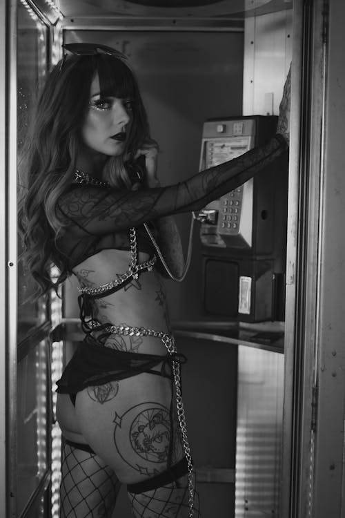 A woman in fishnet stockings and lingerie standing in a phone booth