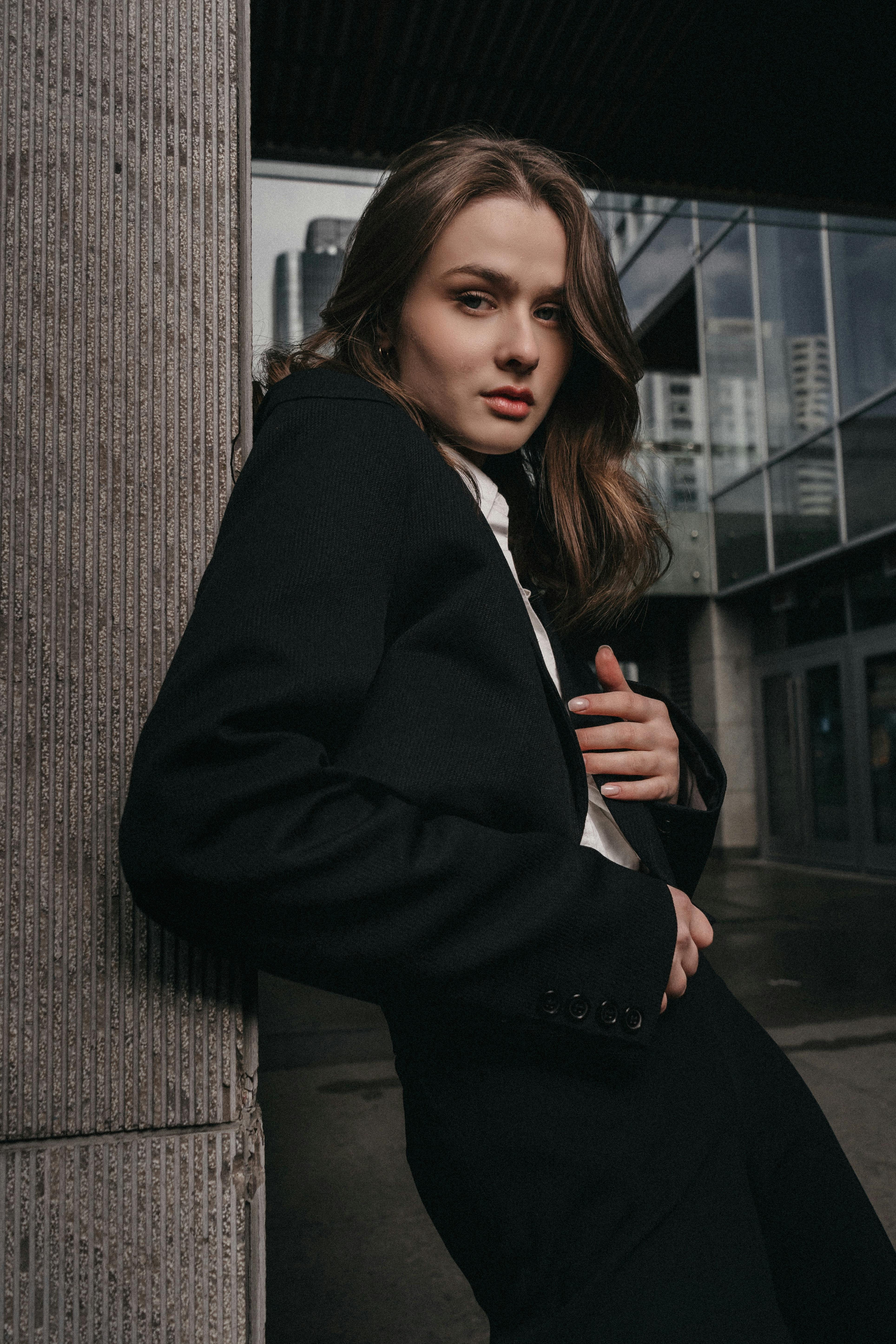 a woman in a suit leaning against a wall