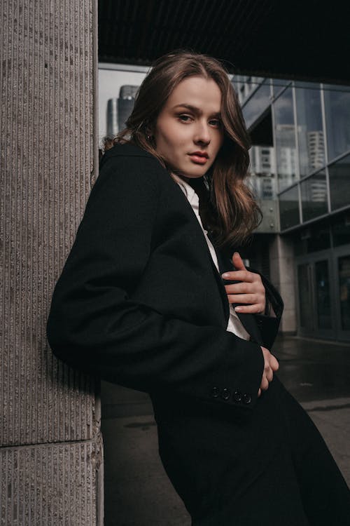 Free A woman in a suit leaning against a wall Stock Photo