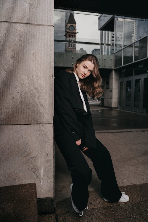 A woman in a suit leaning against a wall