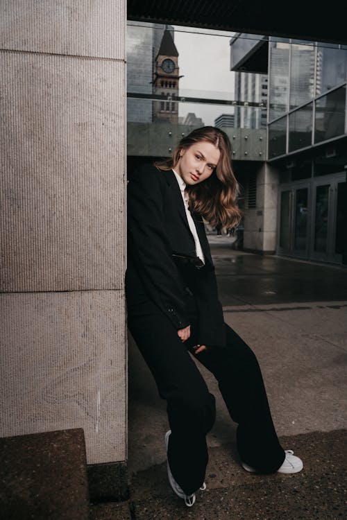 Free A woman in a suit leaning against a wall Stock Photo