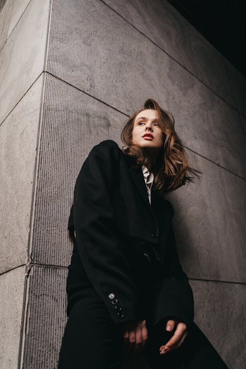 A woman leaning against a wall wearing a black jacket