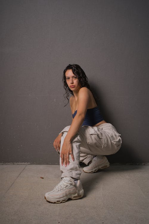 A woman in a white top and pants squatting
