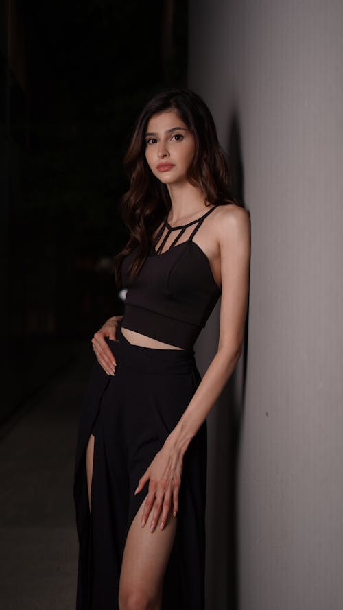 A woman in a black top and skirt posing
