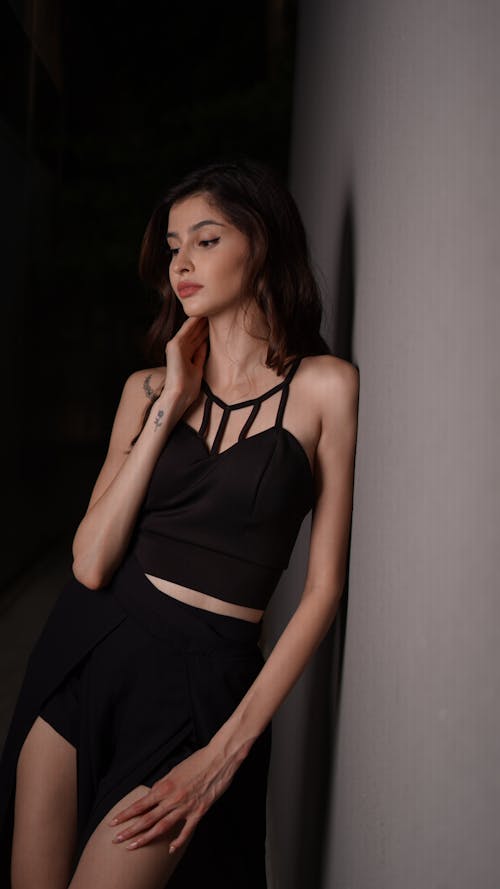 A woman in black top and skirt posing