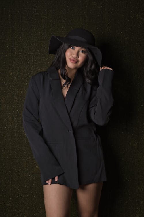 A woman in a black suit and hat posing for a photo
