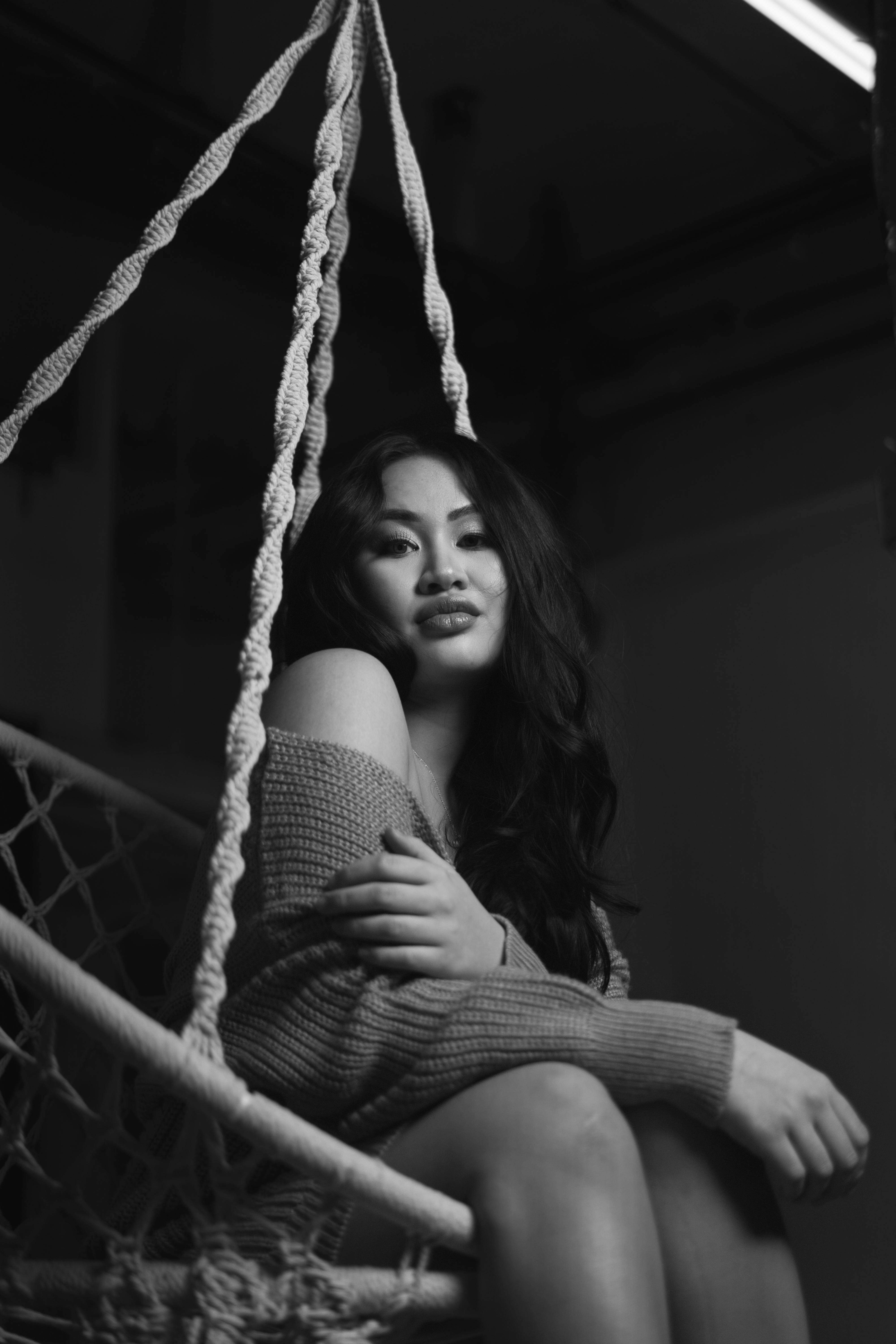 a woman sitting in a hammock in black and white