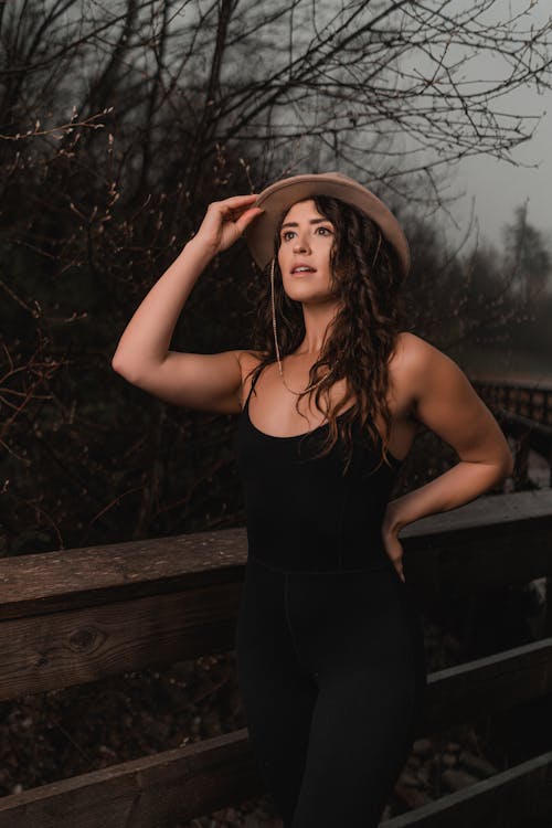 A woman in black pants and hat posing for a portrait