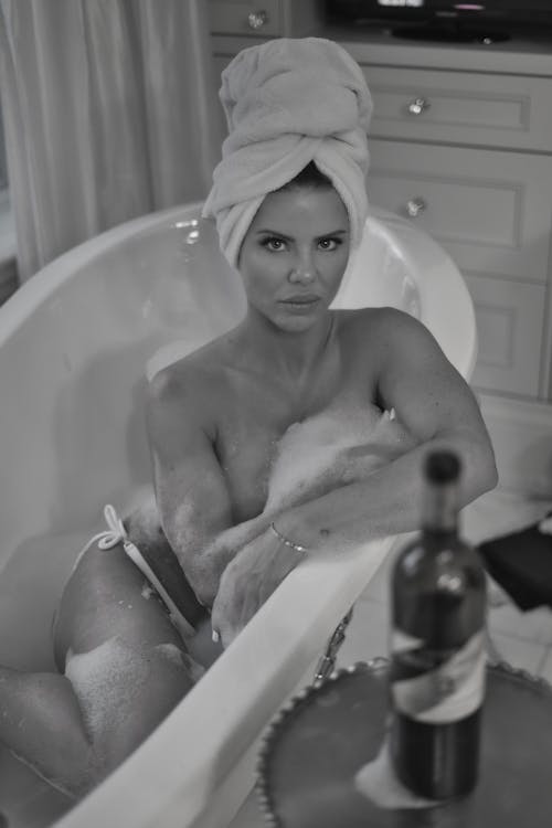 A woman in a bathtub with a towel on her head