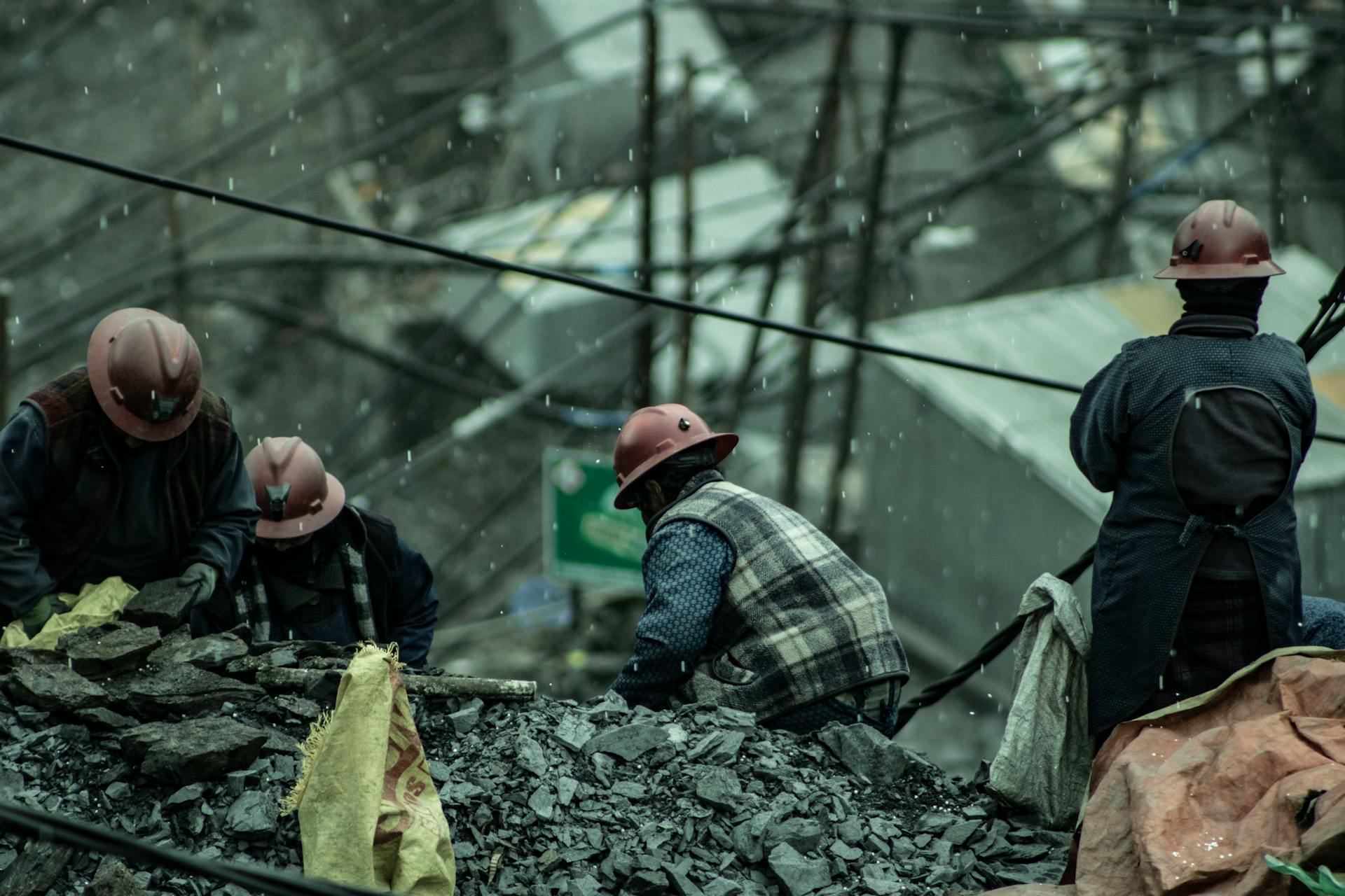 Miners wearing helmets working in rugged outdoor conditions under rain in La Rinconada, Peru.