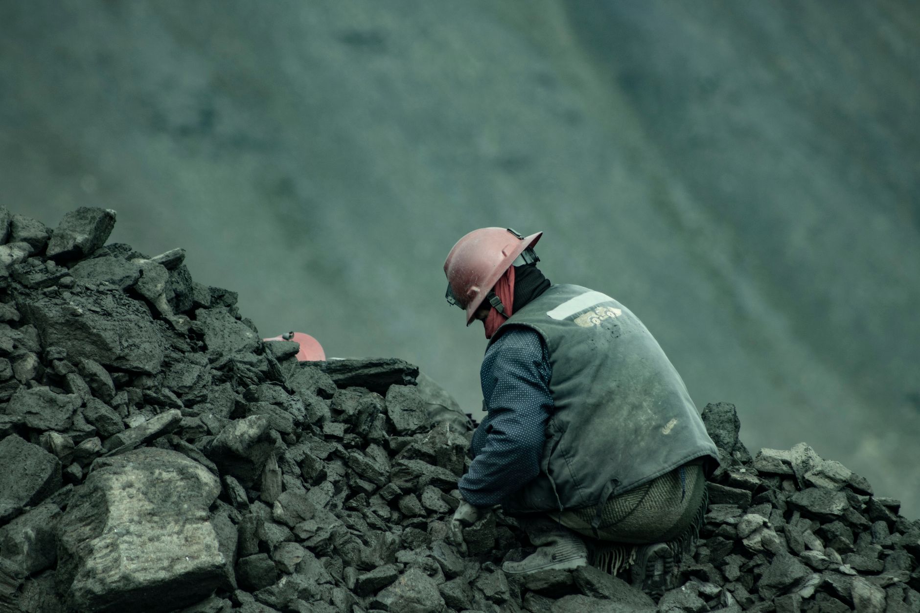 A miner wearing a helmet works in a quarry among rocks in Puno, Peru.