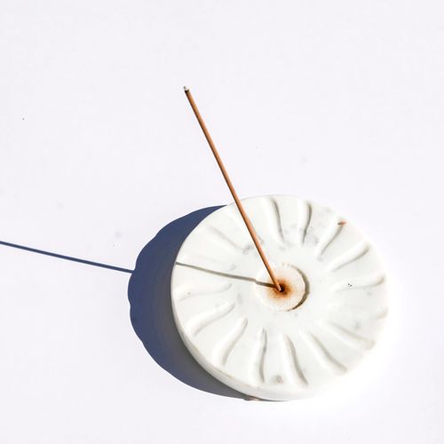 Free A single incense stick in a decorative holder casting a shadow on a white background. Stock Photo