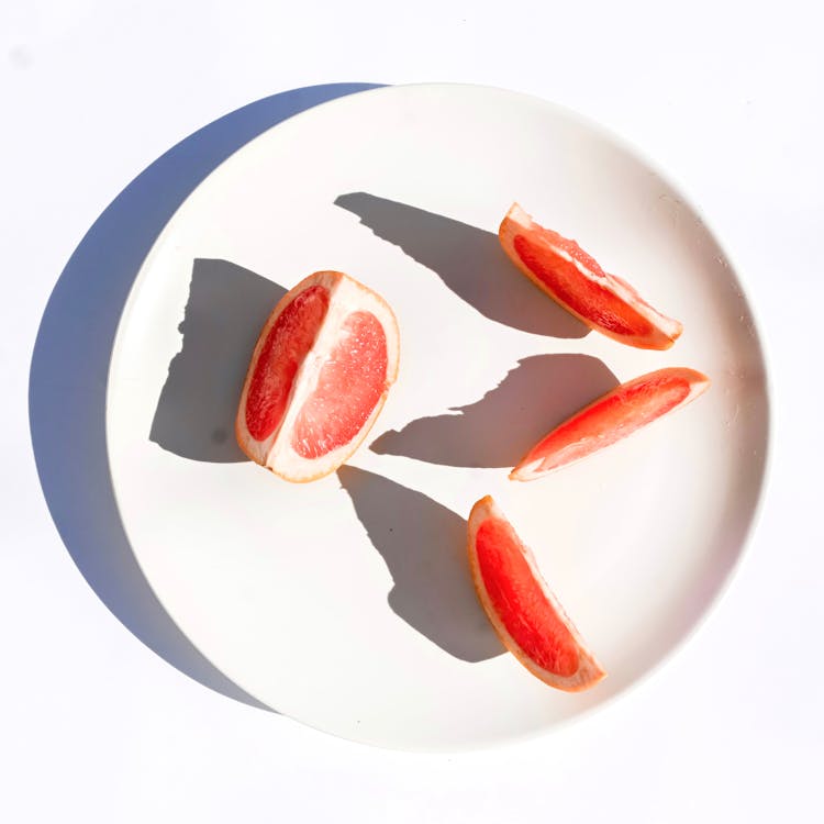 Slices Of Red Grapefruit On A White Plate