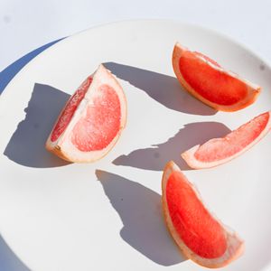 Fresh grapefruit slices on a white plate, photo by Studio Naae on Pexels