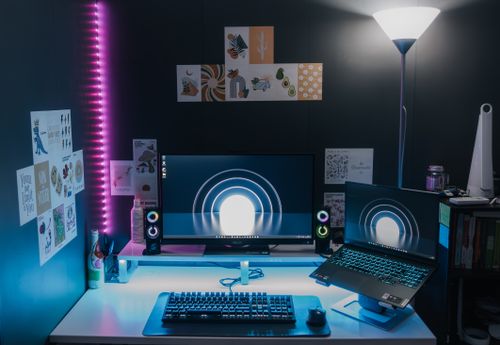 Free Stylish gaming setup featuring dual monitors, LED lighting, and tech accessories for an immersive experience. Stock Photo