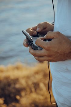 Close-up of a person holding a joystick with ocean and sandy backdrop. Ideal for lifestyle or tech themes.