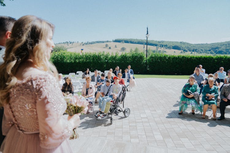 Newlywed Couple And Guests At An Outdoor Wedding Ceremony 