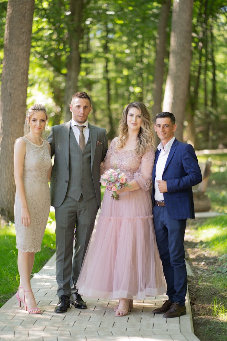 Bride And Groom Posing In A Park With Their Friends