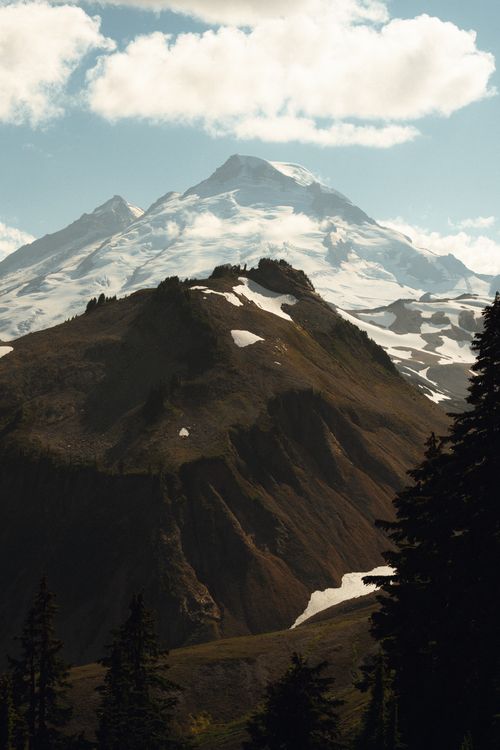 Free Breathtaking view of a snowcapped mountain under bright sky with patches of snow and lush slopes. Stock Photo