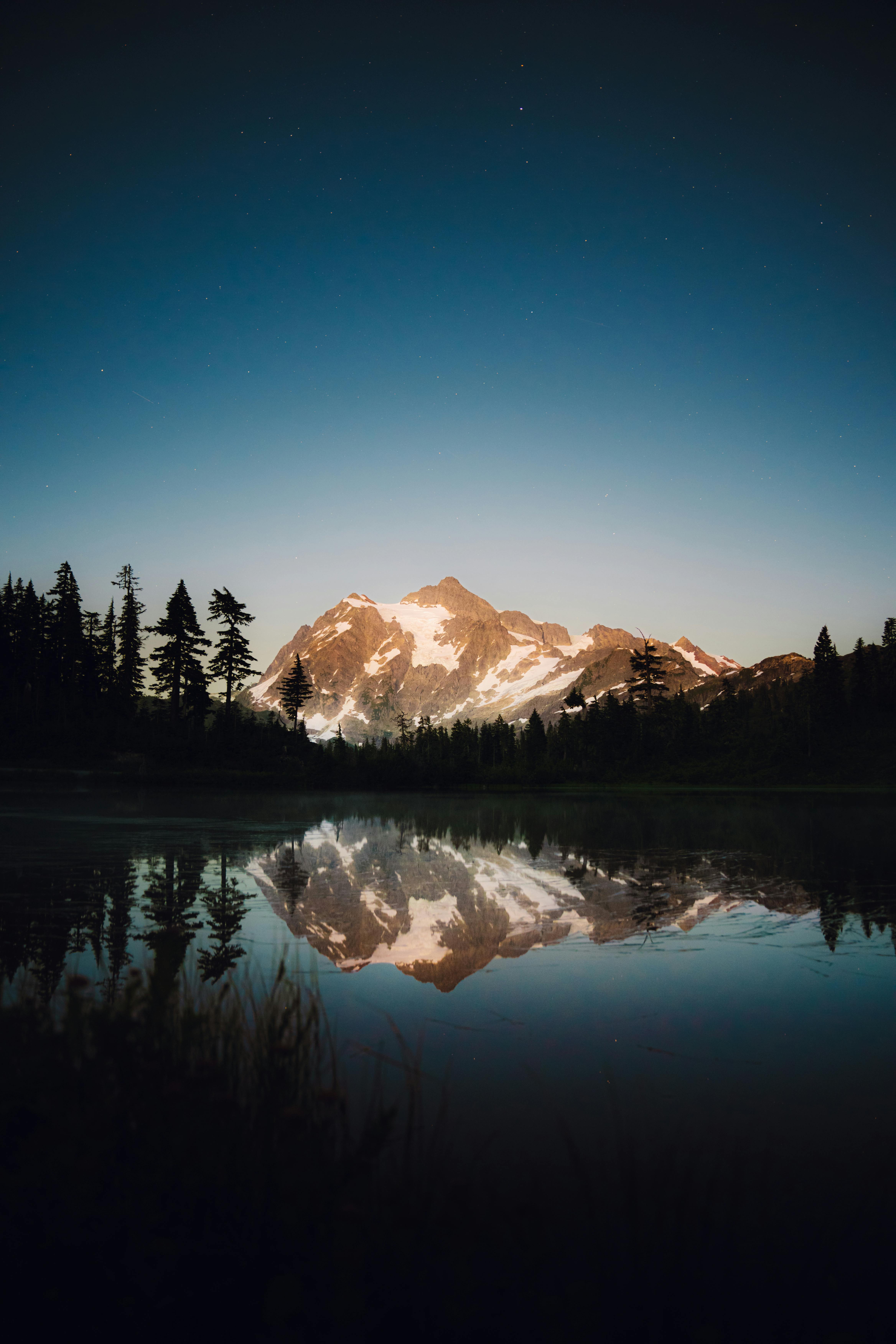 Peaceful twilight view of snowcapped mountains reflecting in a serene lake.