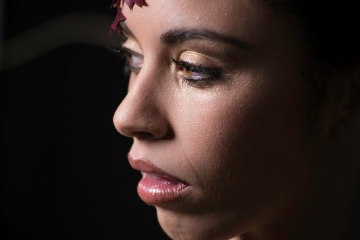 Elegant close-up portrait of a woman with glitter makeup in a studio setting.