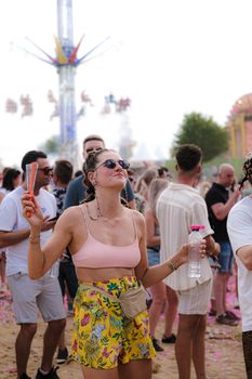 Lively summer festival scene with people enjoying music and rides outdoors.