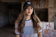 一位年轻女子的肖像，头戴阿迪达斯帽子，身穿白色网状上衣