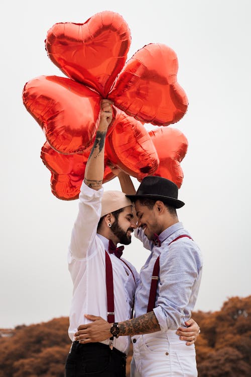 Hombre Mirando A Otro Hombre Sosteniendo Globos