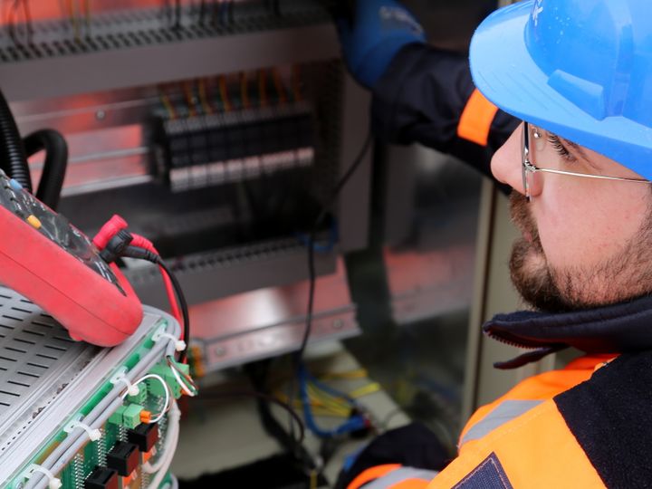 Licensed electrician in safety gear working on a switchboard