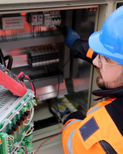Electrician in hard hat working on switchboard