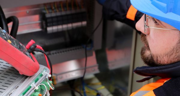 Industrial electrician in safety gear at switchboard