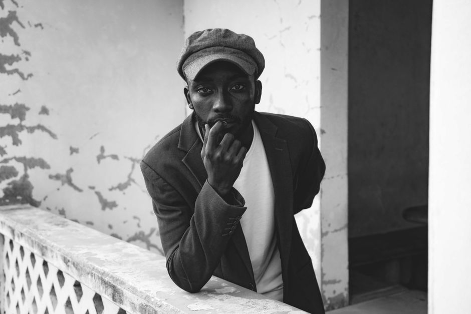 Elegant portrait of a man in a hat and jacket posing thoughtfully in Abuja, Nigeria.