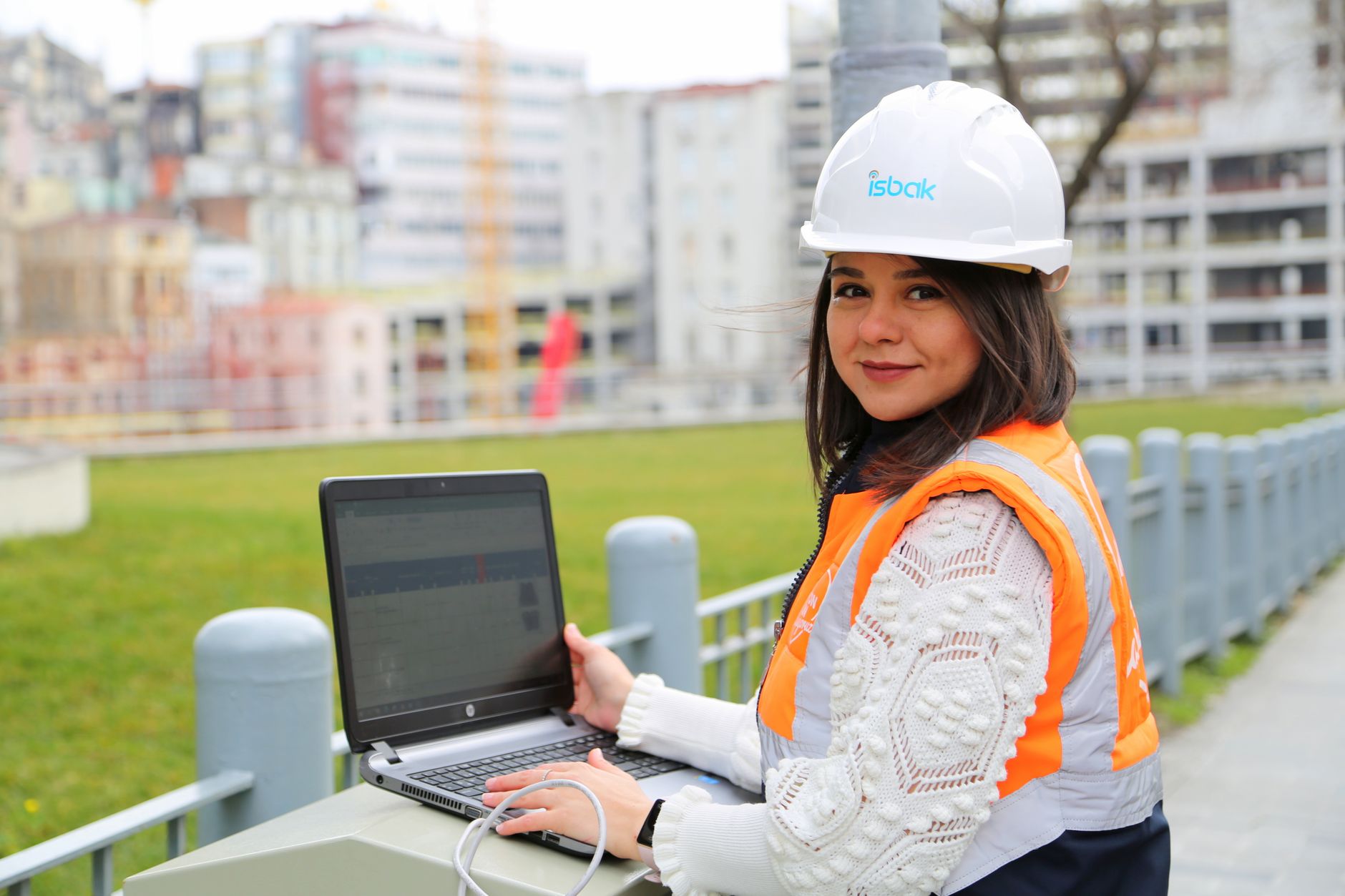 A female engineer using a laptop at a construction site outdoors.