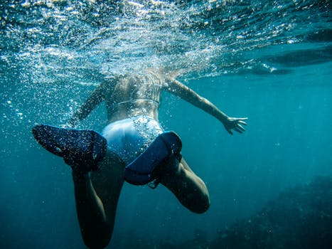 在清澈的海水中，有人戴着脚蹼在水下游泳